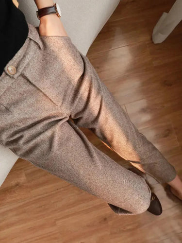 Close-up of a person wearing brown pants on a wooden floor.